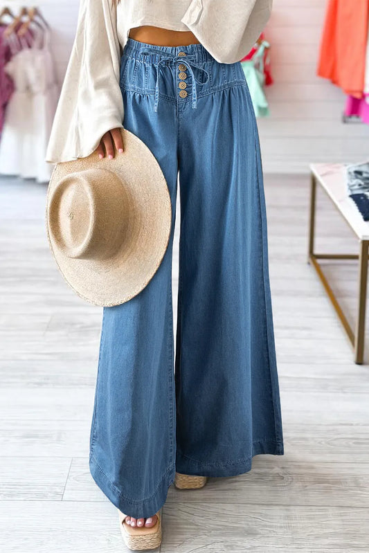 High waisted wide leg denim pants with an elastic waistband, drawstring tie and button front detail. Flowy relaxed fit.