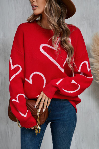 Long sleeve red sweater with two white heart shape prints on sleeves and on front of sweater.