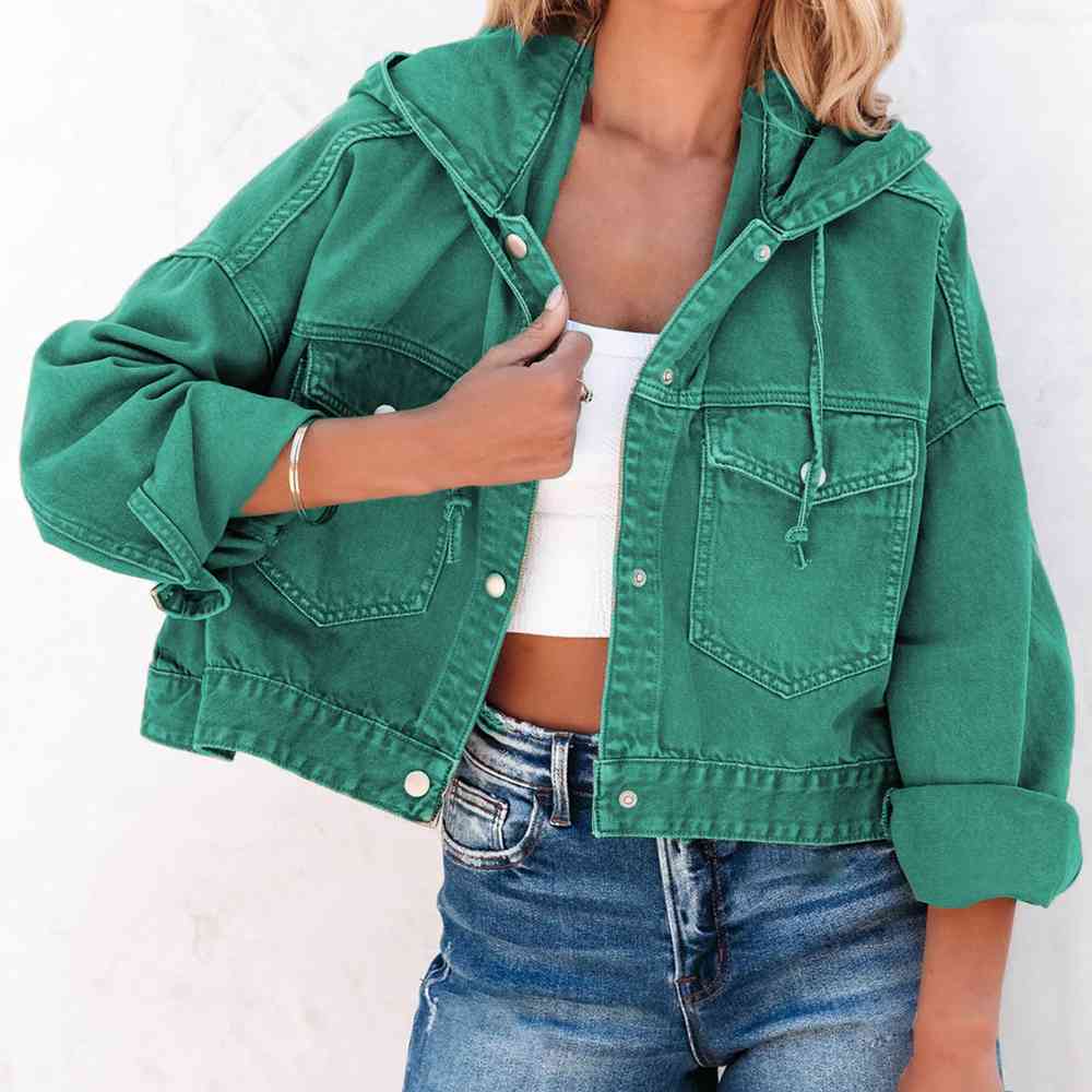 A stylish green oversized hooded denim jacket with a button up front, flap pockets and adjustable drawstring hood. The Jacket features a relaxed fit with rolled-up sleeves, paired with a white crop top and blue jeans for a casual trendy look.